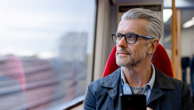 Man on smartphone looks out of train window